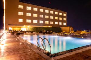 a swimming pool in front of a building at night at Vivanta Chitwan Bharatpur in Bharatpur