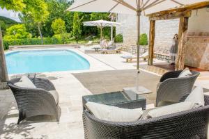 a swimming pool with wicker chairs and an umbrella at Domaine de Saint-Géry - Teritoria in Lascabanes