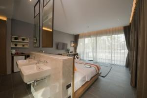 奈汉海滩The Gallery Hotel Nai Harn的一间带两个盥洗盆的浴室和一张位于客房内的床。