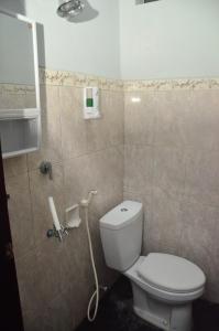 a bathroom with a toilet and a tiled wall at Banyu Homestay in Banyuwangi