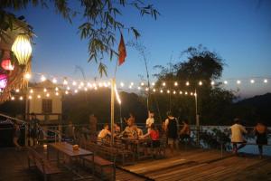 a group of people sitting at tables on a deck with lights at Hahaland in Phong Nha