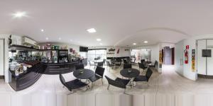 a restaurant with tables and chairs and a bar at Hollyster Hotel in Curitiba