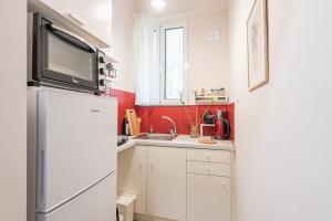 eine Küche mit einem Kühlschrank und einer Mikrowelle in der Unterkunft Cozy studio 5mins walk from Acropolis museum in Athen