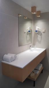 a bathroom with a sink and a mirror and towels at Hospedaria Frangaria in Faro