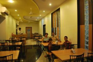 un grupo de personas sentadas en mesas en un restaurante en Kuber Inn, en Shirdi