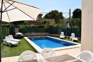 een achtertuin met een zwembad met stoelen en een parasol bij Villa Llobeta in L'Ametlla de Mar