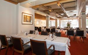 Fletcher Hotel-Restaurant Wolfheze في وولفهيزه: غرفة طعام مع طاولات وكراسي بيضاء