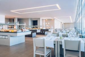 a restaurant with white tables and white chairs at Iberostar Selection Lagos Algarve in Lagos