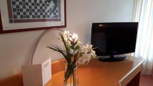 eine Vase mit Blumen auf einem Schreibtisch mit Computermonitor in der Unterkunft Hotel Schlosswald in Triesen
