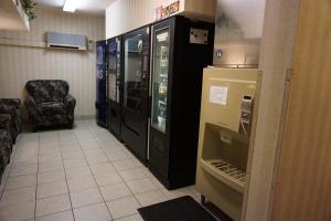 a hallway with a refrigerator and a chair in a room at CenterWay Hotel Buffalo North Near University in Tonawanda