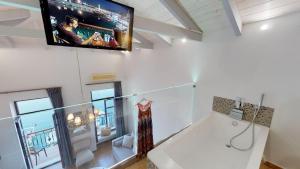 a bathroom with a tub and a tv on the wall at Porto Enetiko Suites in Rethymno Town