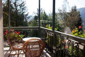 einen Balkon mit 2 Stühlen, einem Tisch und Blumen in der Unterkunft Goverla in Jaremtsche