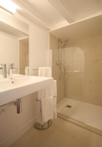 a white bathroom with a sink and a shower at Apartments Paris Centre - At Home Hotel in Paris