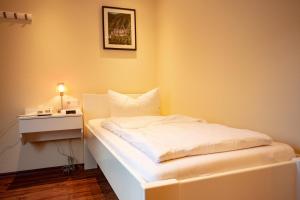 a small bedroom with a white bed and a nightstand at Hotel Mosella in Bullay