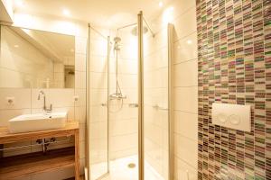 ein Bad mit einer Glasdusche und einem Waschbecken in der Unterkunft Hotel Mosella in Bullay