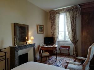a bedroom with a fireplace and a desk and a window at Château des Salles in Saint-Fort-sur-Gironde