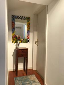 a hallway with a mirror and a table with a vase on it at Haus DreiSeenBlick in Rimsting