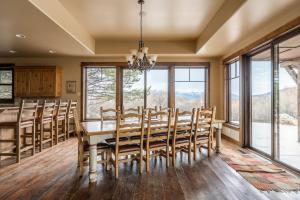 uma sala de jantar com mesa, cadeiras e janelas em Rainbow Point Sabo Cabin em West Yellowstone
