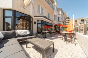 a patio with a couch and tables and chairs at Hotel Cajou in De Panne