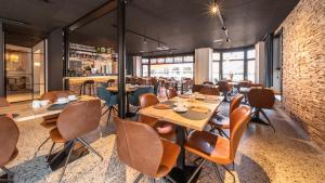 a restaurant with tables and chairs and a brick wall at Hotel Cajou in De Panne