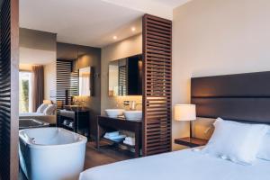 a bedroom with a bed and a tub and a bathroom at Iberostar Selection Lagos Algarve in Lagos