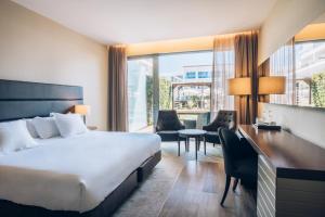 a hotel room with a bed and a desk and chairs at Iberostar Selection Lagos Algarve in Lagos