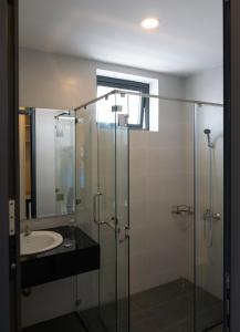 a bathroom with a glass shower and a sink at Summering Hotel in Doc Let