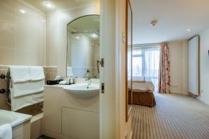 a bathroom with a sink and a mirror and a bed at Langstone Cliff Hotel in Dawlish