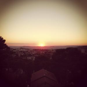a sunset over a city with the sun in the sky at Gîte Polema in Marseille