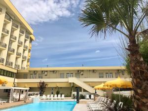 - une vue sur un hôtel avec une piscine et un palmier dans l'établissement Appartamenti Montmartre, à Rimini