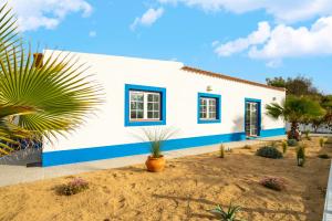 a white house with blue windows and a palm tree at WHome | Comporta Family Beach House in Comporta