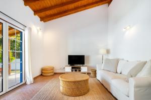 a living room with a white couch and a tv at WHome | Comporta Family Beach House in Comporta