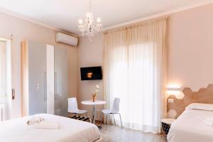 sypialnia z 2 łóżkami, stołem i żyrandolem w obiekcie Roma Talenti Fucini B&B w Rzymie