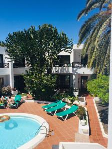 a swimming pool with lounge chairs and a building at Apartamentos Maribel in Puerto del Carmen