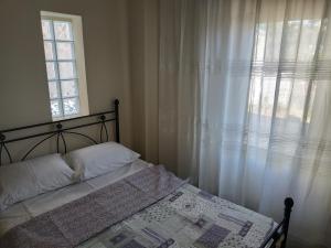 um quarto com uma cama e uma janela com cortinas brancas em Near Airport And metropolitan Artemis George Cozy Home em Artemida