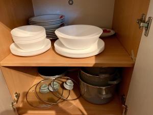a cupboard with plates and bowls on a shelf at Kwatera Orłowska in Gdynia