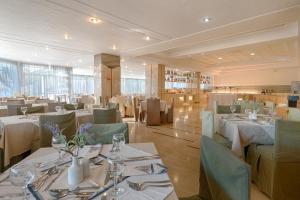 a restaurant with white tables and green chairs at Livadi Nafsika Hotel in Dassia