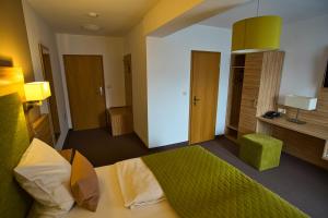 ein Schlafzimmer mit einem Bett mit einer grünen Bettdecke in der Unterkunft Altes Kurhaus Landhotel in Trabelsdorf