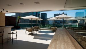 um pátio no último piso com mesas, cadeiras e guarda-sóis em Américas Granada Hotel no Rio de Janeiro
