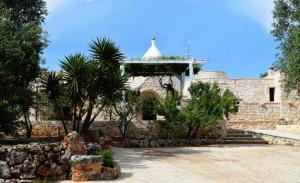 a stone building with a tower and palm trees at Dimore Storiche - Ulivo di Aldo in Martina Franca