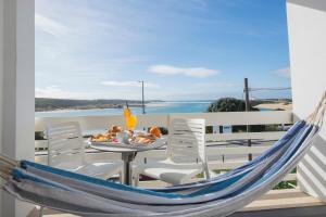 Eine blaue Hängematte auf einem Balkon mit Tisch und Stühlen in der Unterkunft HS Milfontes Beach Hotel - Duna Parque Group in Vila Nova de Milfontes