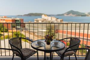 a table with two chairs and two cups on a balcony at Apartments My Przno in Sveti Stefan