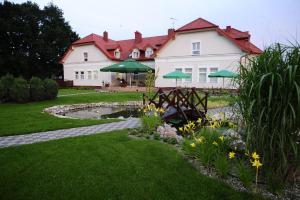 een groot wit huis met een vijver in de tuin bij Hotel Złote Dęby in Warschau