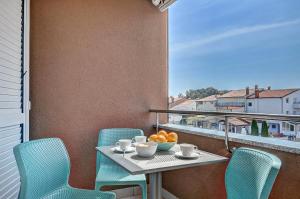 a table with chairs and a bowl of oranges on a balcony at PR Apartment Fazana in Fažana