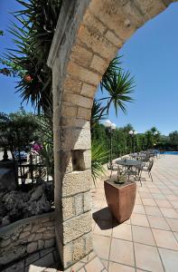 Un arco de piedra con una mesa y sillas en un patio en Hotel Apeneste, en Mattinata