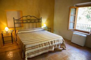 a bedroom with a bed with a striped bedspread and two windows at Casa Vacanze "Casale al Pino" in Riparbella +61 photos