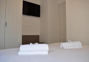 a bed with white sheets and a flat screen tv at Residence Lake Como in Colico
