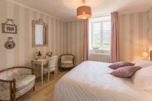 a bedroom with a bed and a desk and a window at Le Manoir de Placy - Chambres d'Hôtes in Clécy