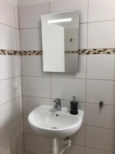 a white bathroom with a sink and a mirror at Pension Kaffeefreunde in Berlin