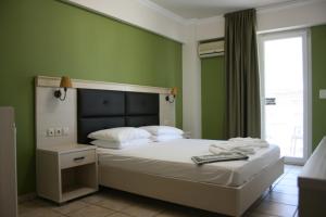 a bedroom with a large bed with green walls at Rea Hotel in Paralia Katerinis